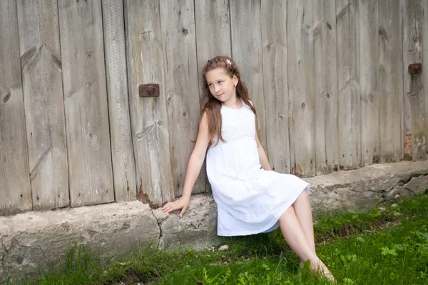 Hermosa Niña Morena Vestido Blanco Sentado Cerca Vieja Casa Madera — Foto de Stock