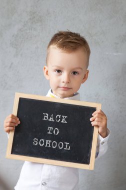Anaokulu çocuğu elinde bir karatahta tutuyor. okul konseptine geri dön