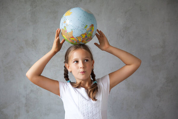 Portrait of a happy school girl with pigtails in a uniform with a globe. Back to school. distance learning from home, Stay at home