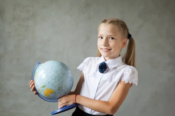Portrait of a happy school girl with ponytails in a uniform with a globe. Back to school. distance learning from home, Stay at home
