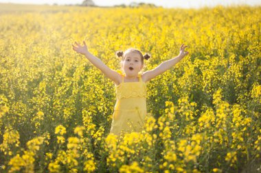 Sarı elbiseli tatlı kız çiçek açan tecavüz tarlasında eğleniyor. Doğa tecavüz tohumu tarlasında çiçek açıyor. Yaz tatili