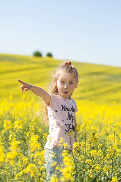 Cute girl having fun in the field of flowering rape. Nature blooms rape seed field. Summer holidays