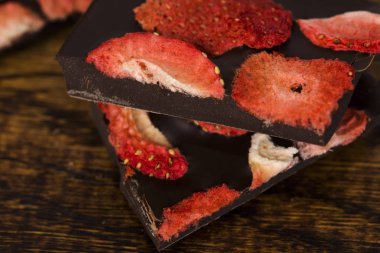 Tahta arka planda çilekli çikolata dilimleri.