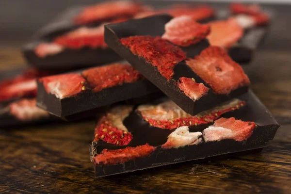 Stack of chocolate slices with strawberry on wooden background — Stock Photo, Image