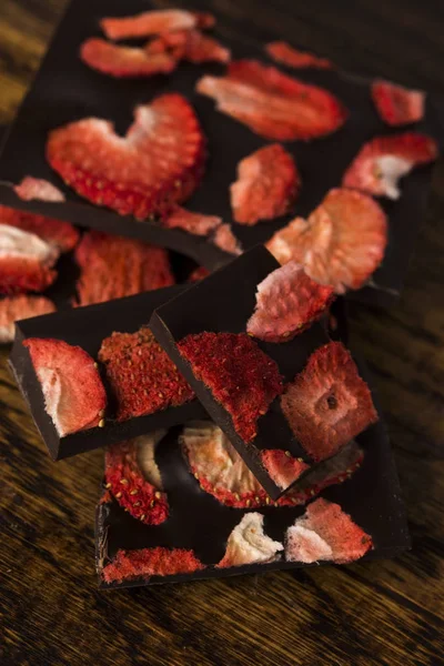 Stos plasterków czekolady z truskawkami na drewnianym tle — Zdjęcie stockowe