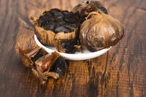 Black garlic on wooden background