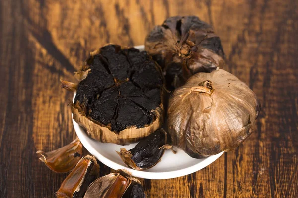 Black Garlic Wooden Background — Stock Photo, Image