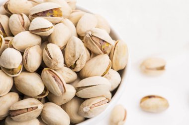 Beyaz arka planda bir kase kavrulmuş fıstık.