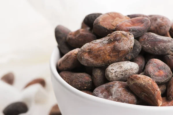 Bowl of cacao beans on a white background — Stock Photo, Image