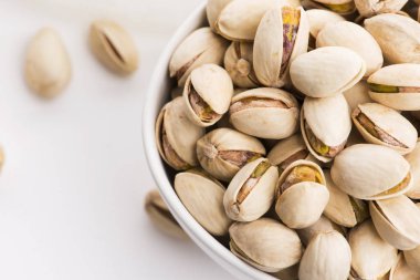 Beyaz arka planda bir kase kavrulmuş fıstık.