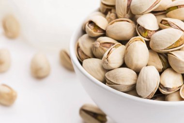 Beyaz arka planda bir kase kavrulmuş fıstık.