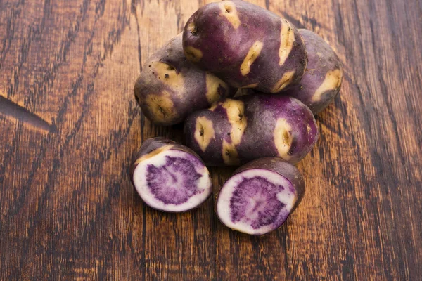 Branco - batata violeta em fundo de madeira. Planta orgânica — Fotografia de Stock