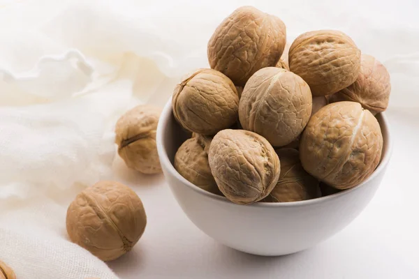 Walnuts in a white ceramic bowl on a white background — Stock Photo, Image