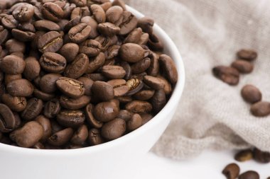 Beyaz arka planda bir kase kahve çekirdeği.