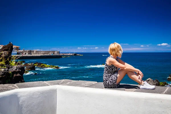 Junge Frau sitzt auf dem Steinzaun über dem Atlantik — Stockfoto