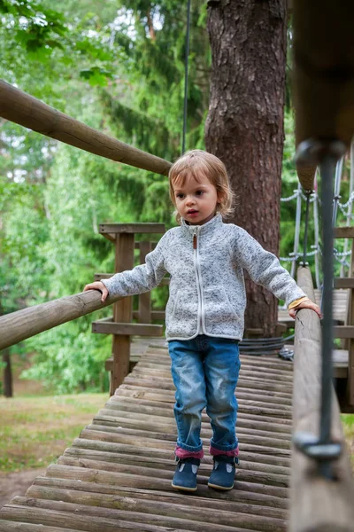 Bebé niña escalando en un patio de juegos de cuerda — Foto de Stock