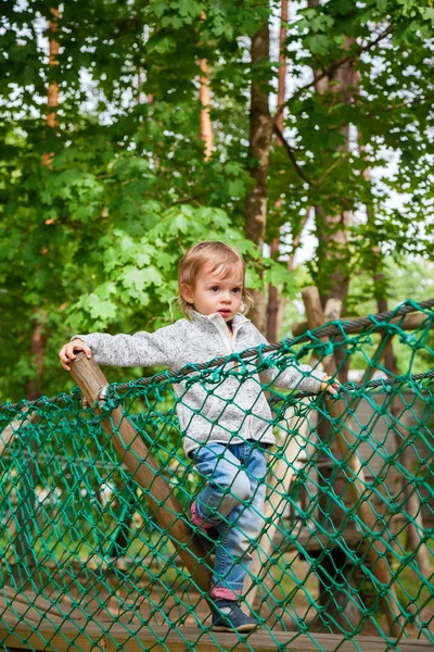 Bebé niña escalando en un patio de juegos de cuerda — Foto de Stock