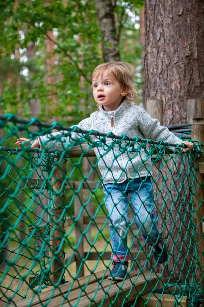 Bebé niña escalando en un patio de juegos de cuerda — Foto de Stock