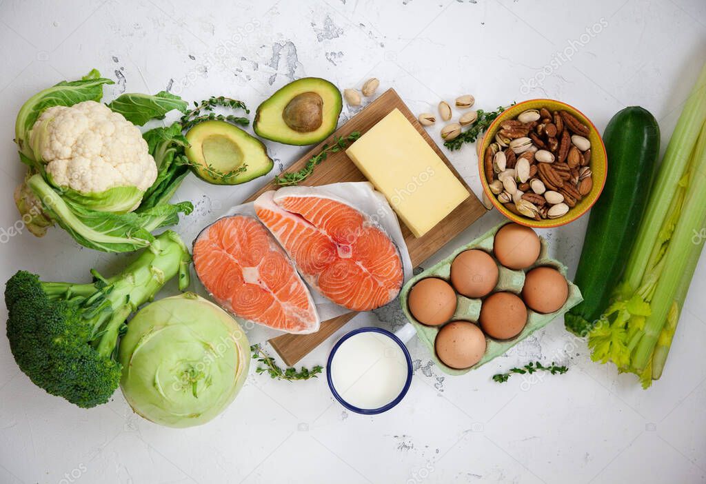 Ketogenic low carbs diet concept. A set of products of the healthy balanced food. Green vegetables, avocado, nuts, salmon, eggs, milk products. Healthy food concept. White background, top view