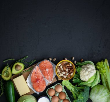 Ketojenik düşük karbonhidrat diyet konsepti. Sağlıklı dengeli gıdaların ürünleri. Yeşil sebze, avokado, fındık, somon, yumurta, süt ürünleri. Sağlıklı gıda konsepti. Siyah arkaplan, üst görünüm, kopyalama alanı