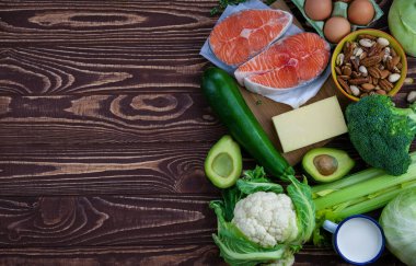 Ketojenik düşük karbonhidrat diyet konsepti. Sağlıklı dengeli gıdaların ürünleri. Yeşil sebze, avokado, fındık, somon, yumurta, süt ürünleri. Sağlıklı gıda konsepti. Ahşap arkaplan, kopyalama alanı, üst görünüm