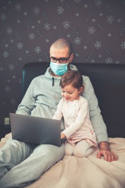 Korunaklı maskeli baba karantina sırasında Coronavirus 'ta çalışıyor. Çocuk evde, anaokulu kapalı. Kızı ona dizüstü bilgisayarda yardım ediyor..