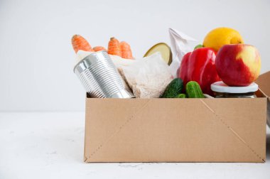 Çeşitli yiyeceklerle birlikte bağış kutusu. Konserve yiyecek, mısır gevreği, meyve, sebze. Beyaz arkaplan, kopyalama alanı.