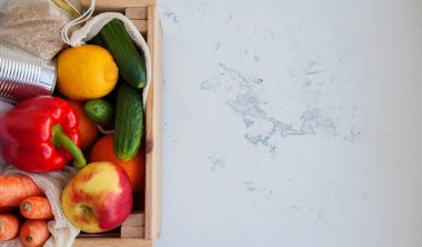 Tahta kutuda bağışlanacak farklı ürünler. Konserve yiyecek, pirinç, meyve ve sebzeler beyaz arka planda, üst manzara, kopyalama alanı