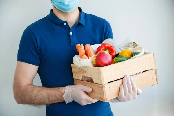Courier man in medical mask and gloves holding a food box. Online food order, delivery during quarantine, coronavirus outbreak. Service quarantine pandemic coronavirus.