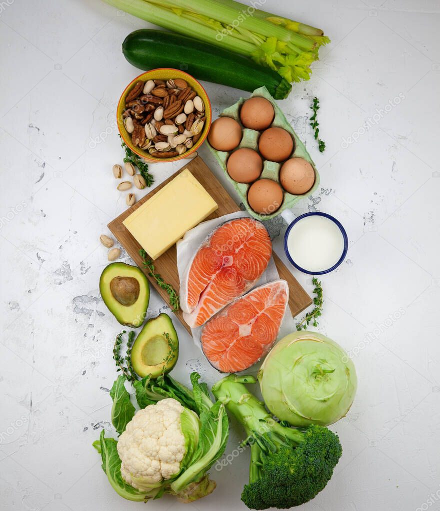 Low carbs diet concept. A set of products of the healthy balanced food. Green vegetables, avocado, nuts, salmon, eggs, milk products. Healthy food concept. White background, flat view