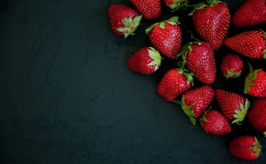 Siyah zemin üzerinde taze kırmızı çilekler, düz yatış, kopyalama alanı