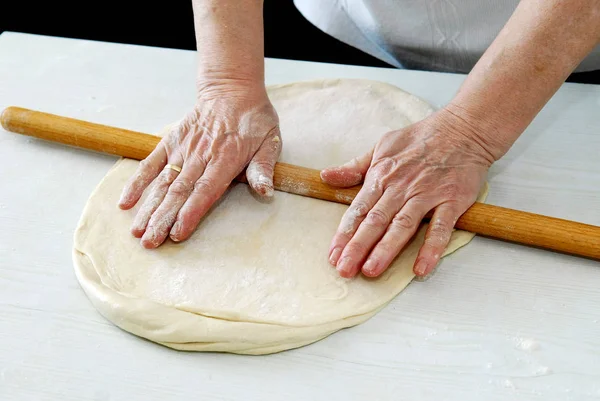 Женщина разворачивает тесто на столе — стоковое фото