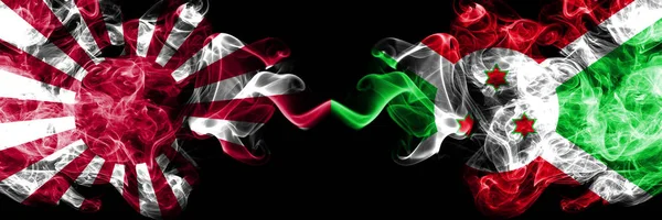 Giappone Sol Levante naval vs Burundi, bandiere mistiche fumose burundesi affiancate. Bandiere astratte di fumo di viaggio di seta colorate spesse — Foto Stock