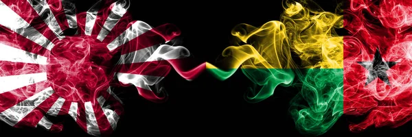 Japan rising sun naval vs Guinea Bissau smoky mystic flags placed side by side. Thick colored silky travel abstract smokes banners — Stock Photo, Image