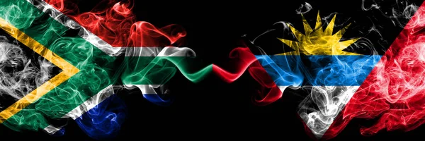 Dél-Afrika vs Antigua és Barbuda füstös misztikus zászlók egymás mellett. Vastag színű selymes elvont füst zászlók koncepció — Stock Fotó
