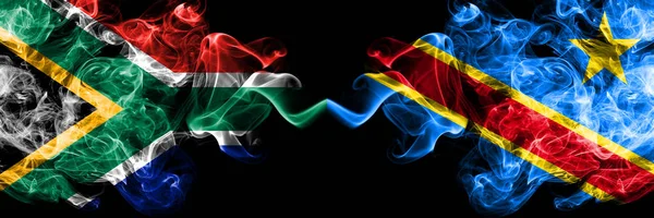 África do Sul vs República Democrática do Congo bandeiras místicas fumegantes colocadas lado a lado. Conceito de bandeiras de fumaça abstrata sedosa de cor grossa — Fotografia de Stock