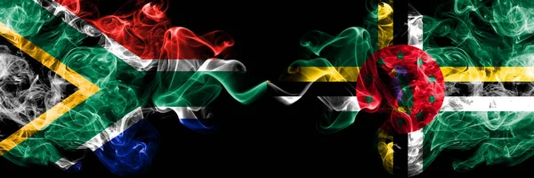 Sydafrika vs Dominica rökiga mystiska flaggor placeras sida vid sida. Tjock färgad silkeslen abstrakt rök flaggor koncept — Stockfoto