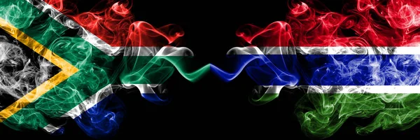 Южная Африка против Гамбии, гамбийские дымящиеся мистические флаги, размещенные бок о бок. Толстые цветные шелковистые абстрактные флаги — стоковое фото