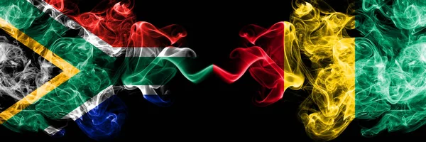Zuid-Afrika vs Guinee, Guinese rokerige mystieke vlaggen naast elkaar geplaatst. Dikke gekleurde zijdeachtige abstracte rook vlaggen concept — Stockfoto