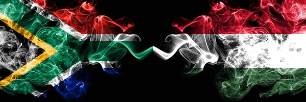 África do Sul vs Hungria, bandeiras místicas fumegantes húngaras colocadas lado a lado. Conceito de bandeiras de fumaça abstrata sedosa de cor grossa — Fotografia de Stock