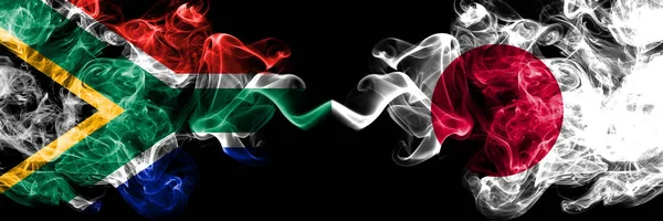Zuid-Afrika vs Japan, Japanse rokerige mystieke vlaggen naast elkaar geplaatst. Dikke gekleurde zijdeachtige abstracte rook vlaggen concept — Stockfoto