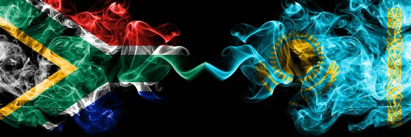 Dél-Afrika vs Kazahsztán, Kazahsztáni füstös misztikus zászlók egymás mellett. Vastag színű selymes elvont füst zászlók koncepció — Stock Fotó