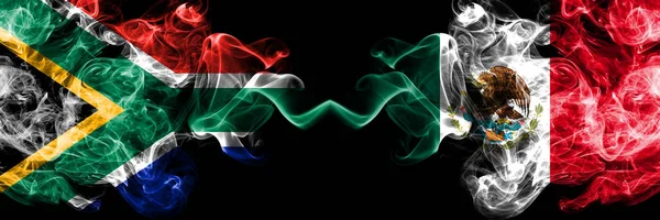 Νότια Αφρική εναντίον Μεξικού, Μεξικάνικη καπνιστή μυστικιστική σημαίες τοποθετούνται δίπλα-δίπλα. Χοντρό χρώμα μεταξένια αφηρημένη έννοια σημαίες καπνού — Φωτογραφία Αρχείου