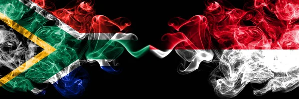 Νότια Αφρική εναντίον Μονακό, Monacan καπνιστή μυστικιστική σημαίες τοποθετούνται δίπλα-δίπλα. Χοντρό χρώμα μεταξένια αφηρημένη έννοια σημαίες καπνού — Φωτογραφία Αρχείου