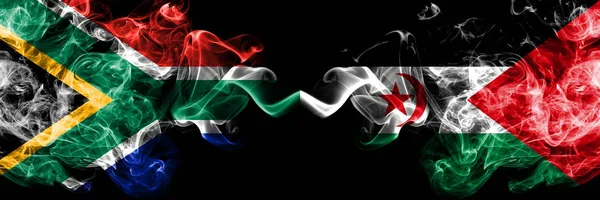 Zuid-Afrika vs Sahrawi rokerige mystieke vlaggen naast elkaar geplaatst. Dikke gekleurde zijdeachtige abstracte rook vlaggen concept — Stockfoto