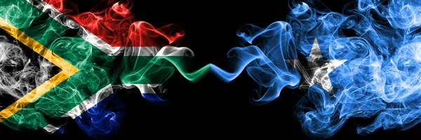 Sudáfrica vs Somalia, banderas místicas humeantes somalíes colocadas una al lado de la otra. concepto de banderas de humo abstracto sedoso de color grueso — Foto de Stock