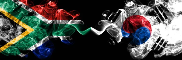 Sydafrika vs Sydkorea, koreanska rökiga mystiska flaggor placerade sida vid sida. Tjock färgad silkeslen abstrakt rök flaggor koncept — Stockfoto