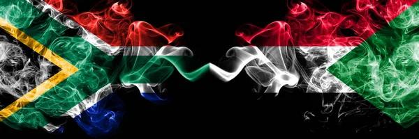 Sudafrica vs Sudan, bandiere mistiche fumose sudanesi affiancate. Concetto di bandiere di fumo astratte di seta colorate spesse — Foto Stock