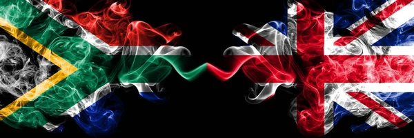 Etelä-Afrikka vs Iso-Britannia, Brittiläinen savuinen mystinen liput sijoitetaan vierekkäin. Paksu värillinen silkkinen abstrakti savu liput käsite — kuvapankkivalokuva