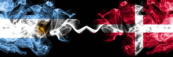 Argentina vs Dinamarca, banderas de fuego místicas ahumadas danesas colocadas una al lado de la otra. concepto de banderas de humo abstracto sedoso de color grueso — Foto de Stock